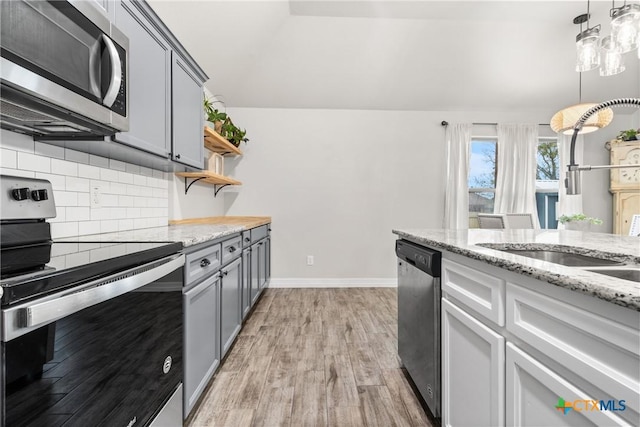 kitchen with gray cabinets, tasteful backsplash, sink, stainless steel appliances, and light hardwood / wood-style flooring