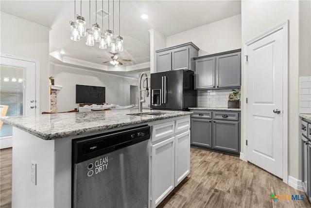 kitchen featuring decorative light fixtures, a center island with sink, high end black fridge, gray cabinets, and dishwasher