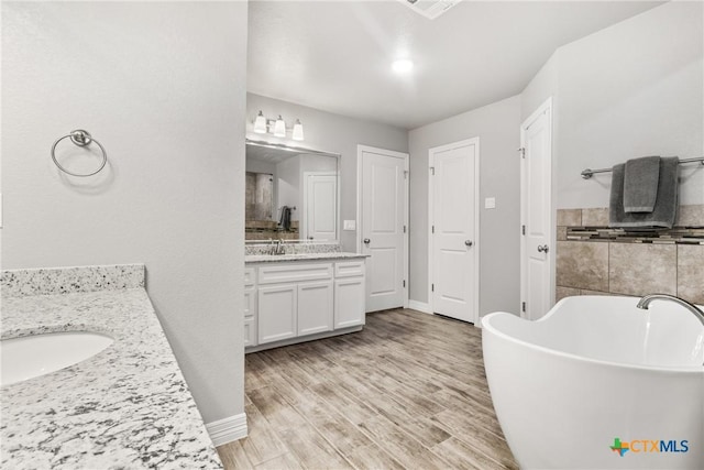 bathroom featuring a tub to relax in, vanity, and wood-type flooring