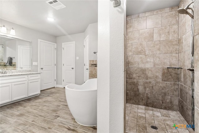 bathroom with hardwood / wood-style flooring, vanity, and plus walk in shower