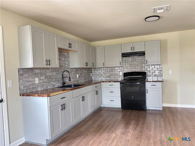 710 E 5th St, Nixon, TX 78140 - kitchen featuring black electric range oven, dark wood finished floors, backsplash, under cabinet range hood, and dark countertops