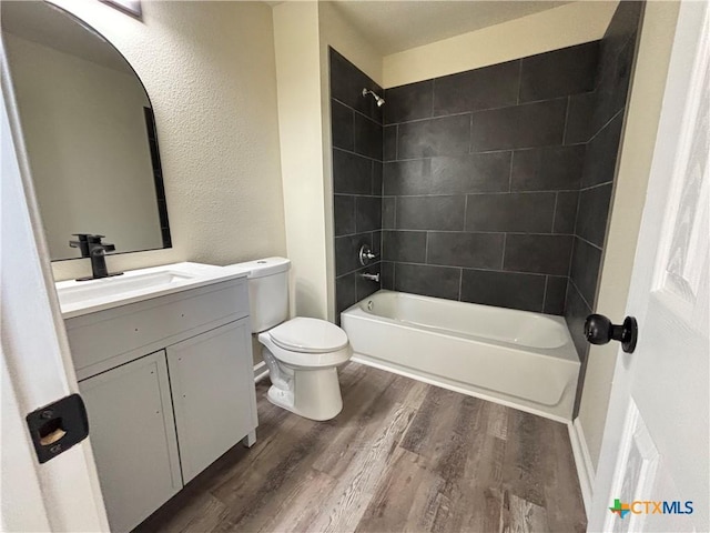 710 E 5th St, Nixon, TX 78140 - full bathroom featuring wood finished floors, vanity, shower / tub combination, and a textured wall