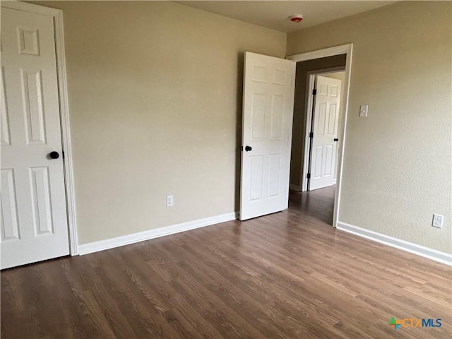 710 E 5th St, Nixon, TX 78140 - unfurnished bedroom featuring dark wood-style flooring and baseboards