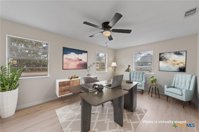 home office with light wood-type flooring, baseboards, visible vents, and a ceiling fan