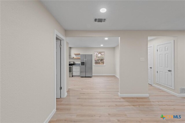 hallway with light wood-type flooring, baseboards, and visible vents