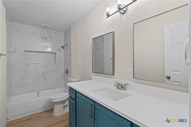 full bathroom featuring tiled shower / bath, wood-type flooring, vanity, toilet, and a notable chandelier