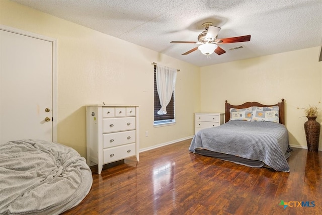 bedroom with a textured ceiling, ceiling fan, and dark wood-type flooring