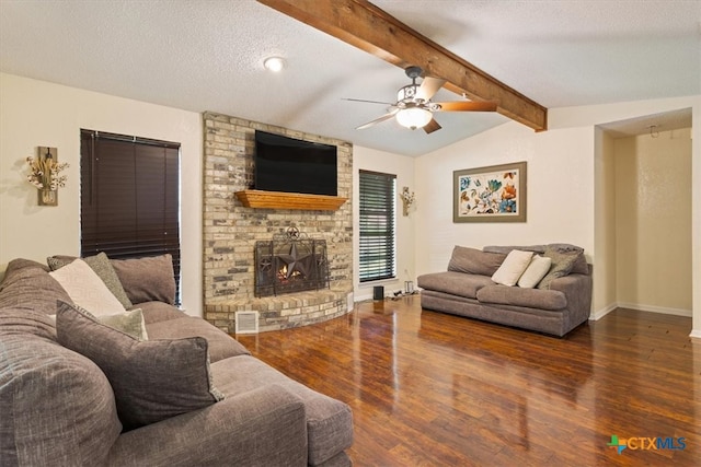 living room with a textured ceiling, ceiling fan, dark wood-type flooring, a fireplace, and vaulted ceiling with beams