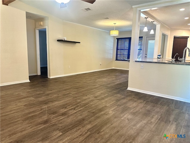 unfurnished living room with sink, crown molding, dark hardwood / wood-style floors, ceiling fan, and a textured ceiling