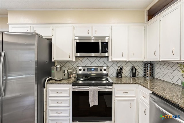 kitchen featuring dark stone countertops, white cabinetry, decorative backsplash, and appliances with stainless steel finishes