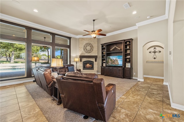 living room with ornamental molding, ceiling fan, light tile patterned floors, and a large fireplace