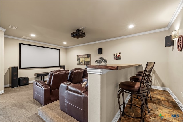 carpeted home theater room featuring indoor bar and crown molding