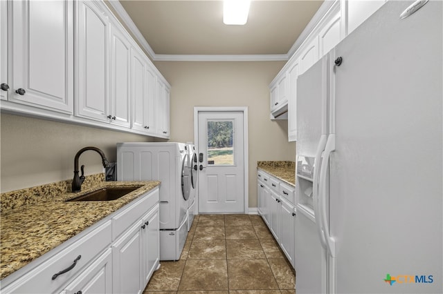 clothes washing area featuring cabinets, sink, crown molding, washing machine and dryer, and dark tile patterned flooring