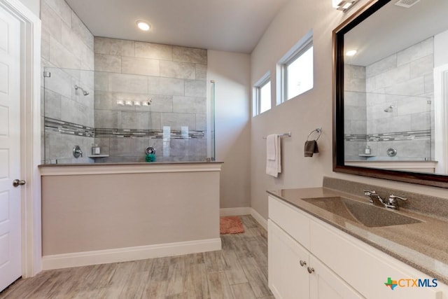 bathroom with vanity, wood-type flooring, and tiled shower