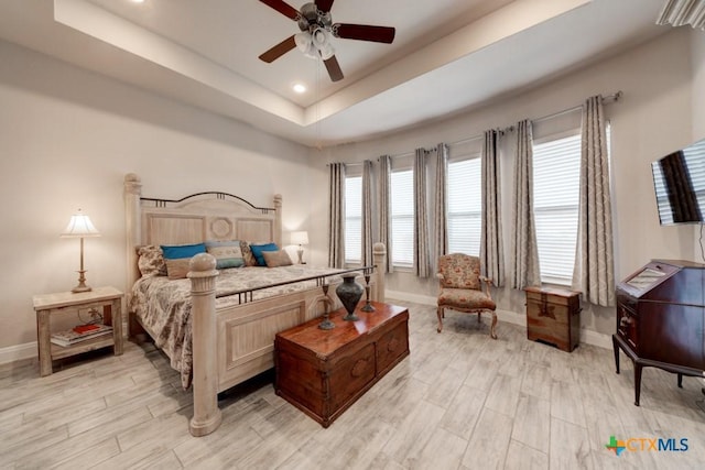 bedroom featuring light hardwood / wood-style floors, a raised ceiling, and ceiling fan