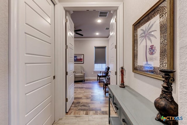 hall with ornamental molding and light hardwood / wood-style flooring