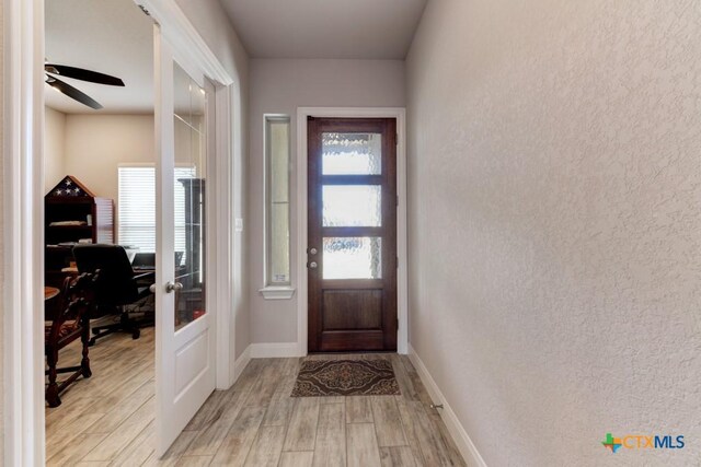 doorway with ceiling fan and light hardwood / wood-style floors