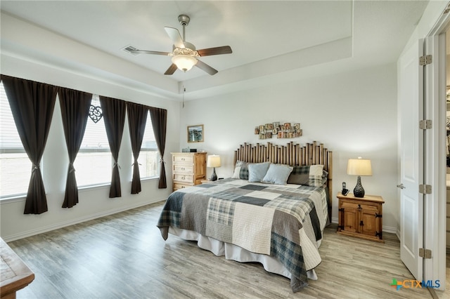 19500 Chayton Cir, Pflugerville, TX 78660 - bedroom featuring light wood-style flooring, baseboards, ceiling fan, and a tray ceiling