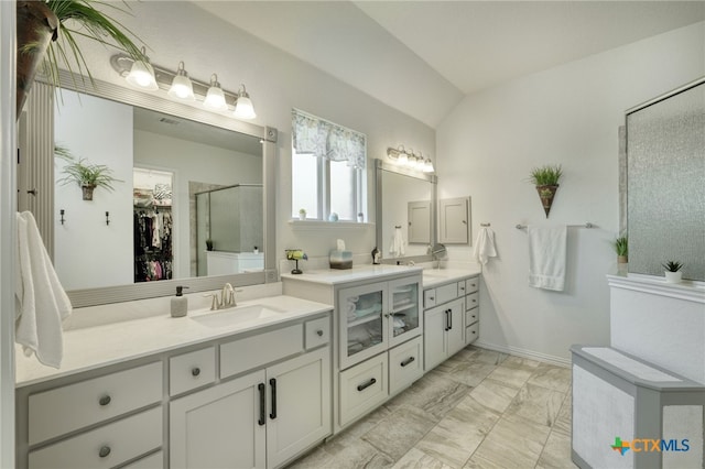 19500 Chayton Cir, Pflugerville, TX 78660 - bathroom featuring vaulted ceiling, marble look tiles, vanity, an enclosed shower, and a walk in closet