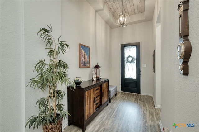 19500 Chayton Cir, Pflugerville, TX 78660 - foyer featuring light wood-style flooring, baseboards, a textured wall, a chandelier, and a tray ceiling