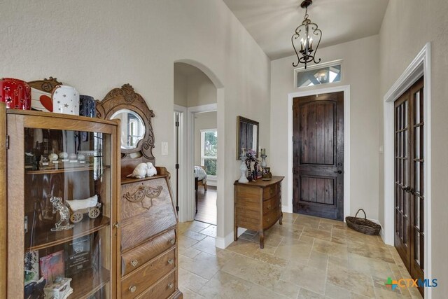 108 Westfield Vw, La Vernia, TX 78121 - foyer with arched walkways, stone tile floors, plenty of natural light, a chandelier, and a high ceiling
