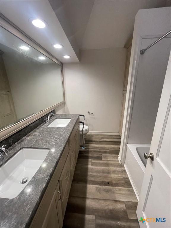 1505 E Park Ave, Victoria, TX 77901 - bathroom with wood finished floors, double vanity, tub / shower combination, and recessed lighting