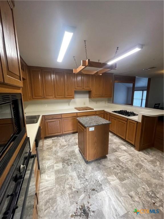 1505 E Park Ave, Victoria, TX 77901 - kitchen with black appliances, a kitchen island, a peninsula, and brown cabinetry