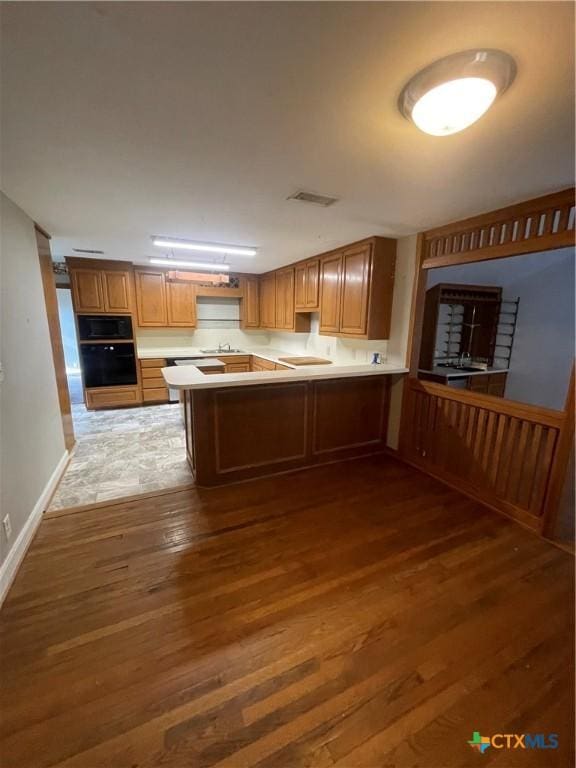 1505 E Park Ave, Victoria, TX 77901 - kitchen featuring wood finished floors, a peninsula, light countertops, black appliances, and brown cabinets