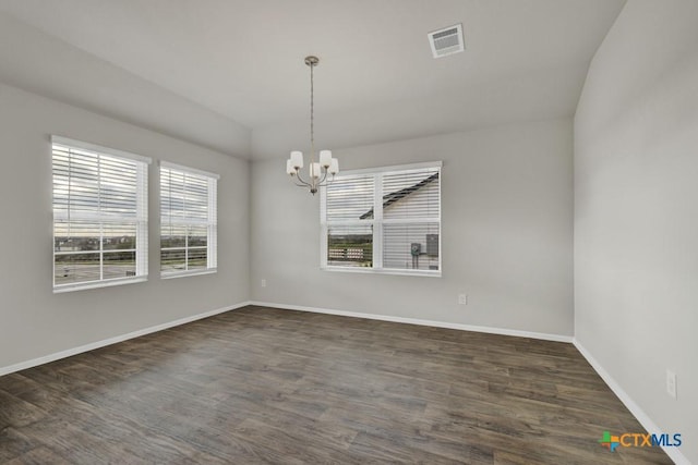 unfurnished room with plenty of natural light, dark hardwood / wood-style flooring, and a chandelier