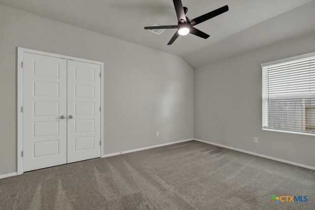 unfurnished bedroom with carpet, lofted ceiling, ceiling fan, and a closet