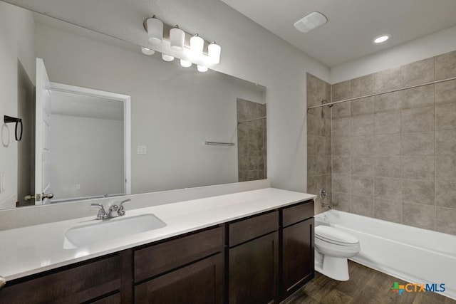 full bathroom with tiled shower / bath combo, vanity, hardwood / wood-style flooring, and toilet