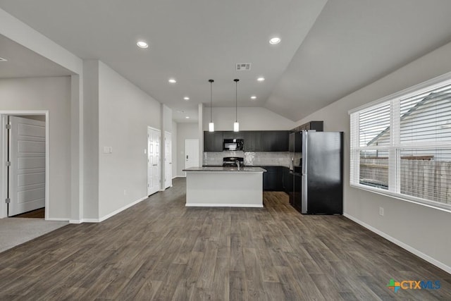 kitchen featuring pendant lighting, stainless steel refrigerator, tasteful backsplash, dark hardwood / wood-style flooring, and a center island with sink