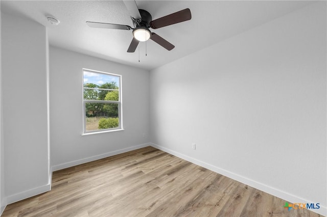 unfurnished room featuring ceiling fan, light wood-style flooring, and baseboards