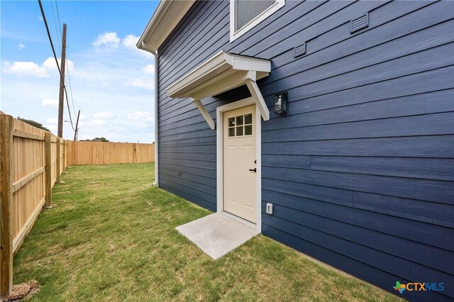 property entrance featuring a yard and fence