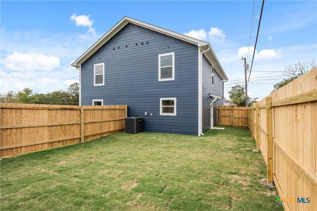 back of property with a fenced backyard, a lawn, and central AC unit