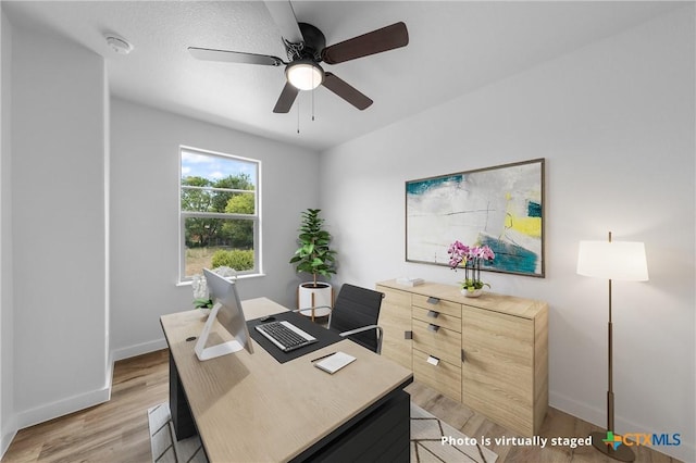 office space with light wood-style floors, ceiling fan, and baseboards