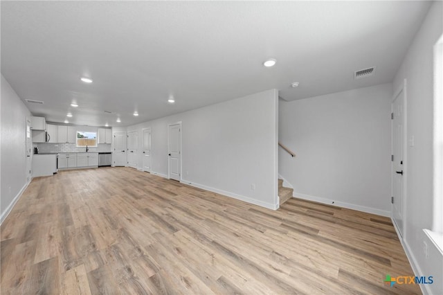 unfurnished living room featuring recessed lighting, visible vents, baseboards, stairway, and light wood-type flooring