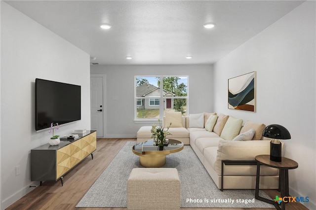 living room with light wood finished floors, baseboards, and recessed lighting