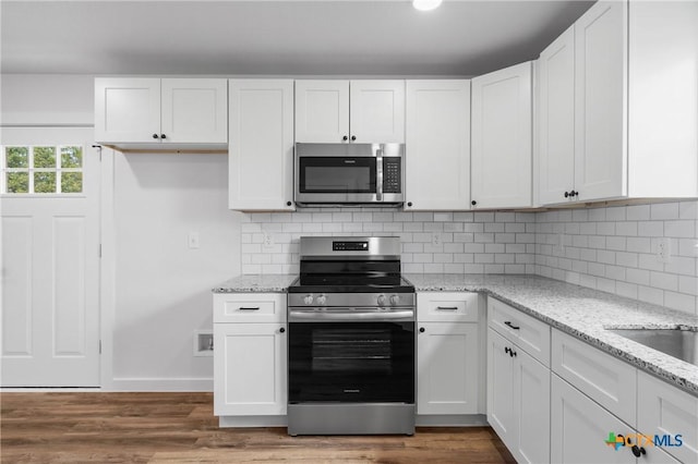 kitchen featuring backsplash, white cabinetry, stainless steel appliances, and dark wood-style flooring