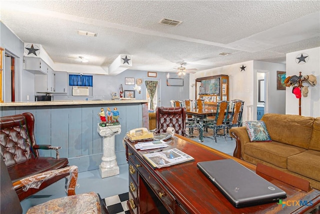 living room with ceiling fan, a wall mounted air conditioner, and a textured ceiling