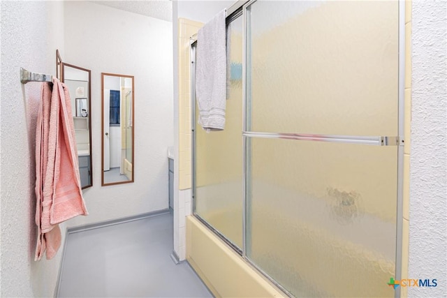 bathroom with combined bath / shower with glass door and a textured ceiling