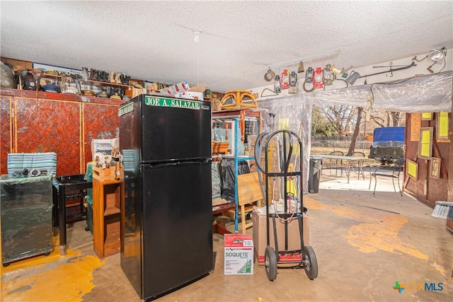 kitchen with concrete floors, a textured ceiling, and black fridge