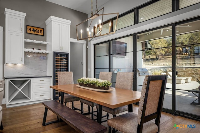 dining area featuring dark wood-type flooring, beverage cooler, and a chandelier