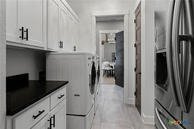 laundry room with light tile patterned flooring, cabinets, and washing machine and dryer