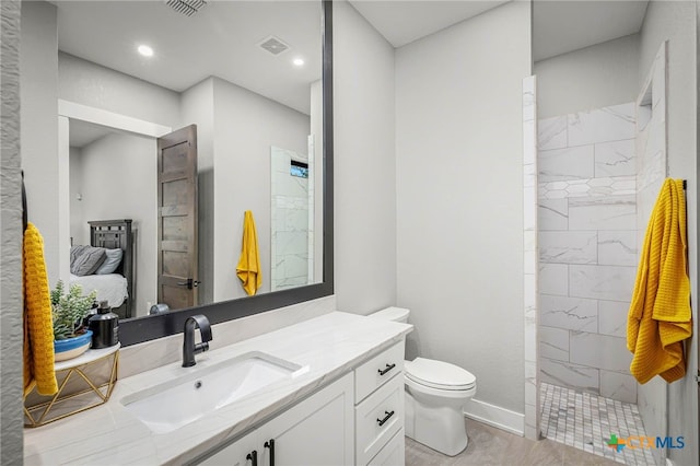 bathroom featuring vanity, toilet, and a tile shower