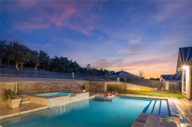 pool at dusk featuring an in ground hot tub