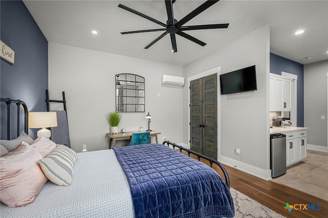 bedroom with ceiling fan, a wall mounted air conditioner, refrigerator, and light hardwood / wood-style flooring