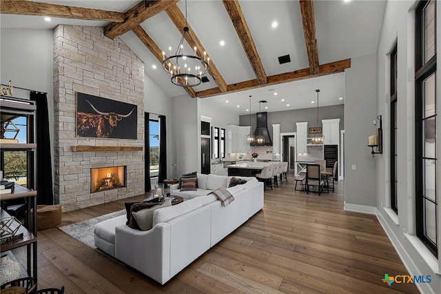 living room with high vaulted ceiling, a chandelier, a fireplace, and light hardwood / wood-style flooring