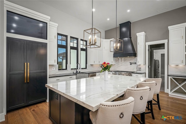 kitchen with premium range hood, a kitchen bar, a center island, hanging light fixtures, and white cabinets