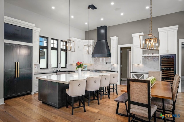 kitchen featuring pendant lighting, a kitchen island, custom range hood, and white cabinets